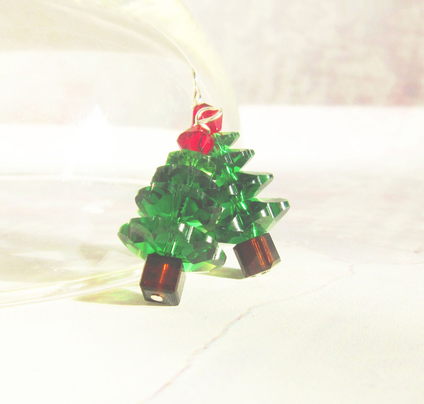 The Crystal Christmas Tree Earrings – Sterling Silver Holiday Jewelry feature festive evergreen shapes with stacked green crystals, brown bases, and a red bead topper, all displayed against a light background.