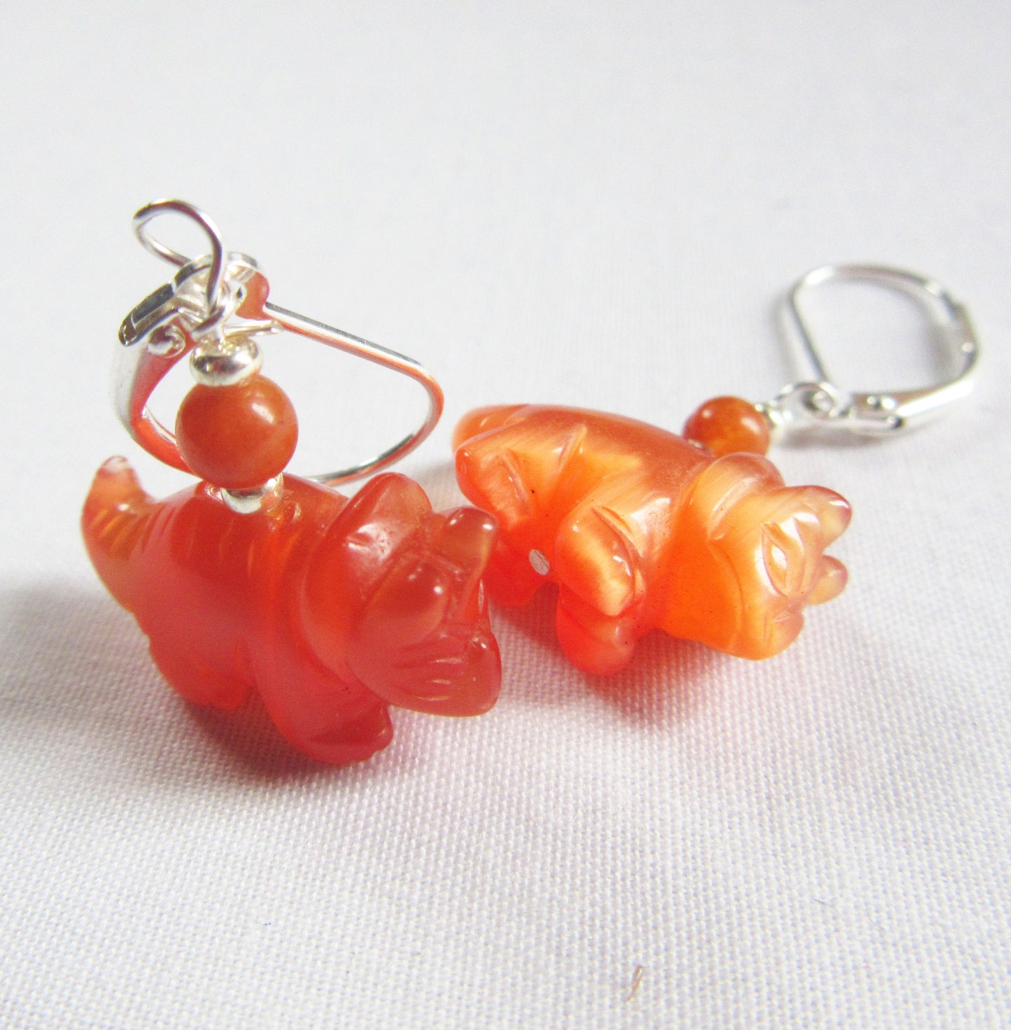 Triceratops earrings displayed on a colorful background - unique dinosaur earrings made from natural stone, a whimsical accessory for any outfit.