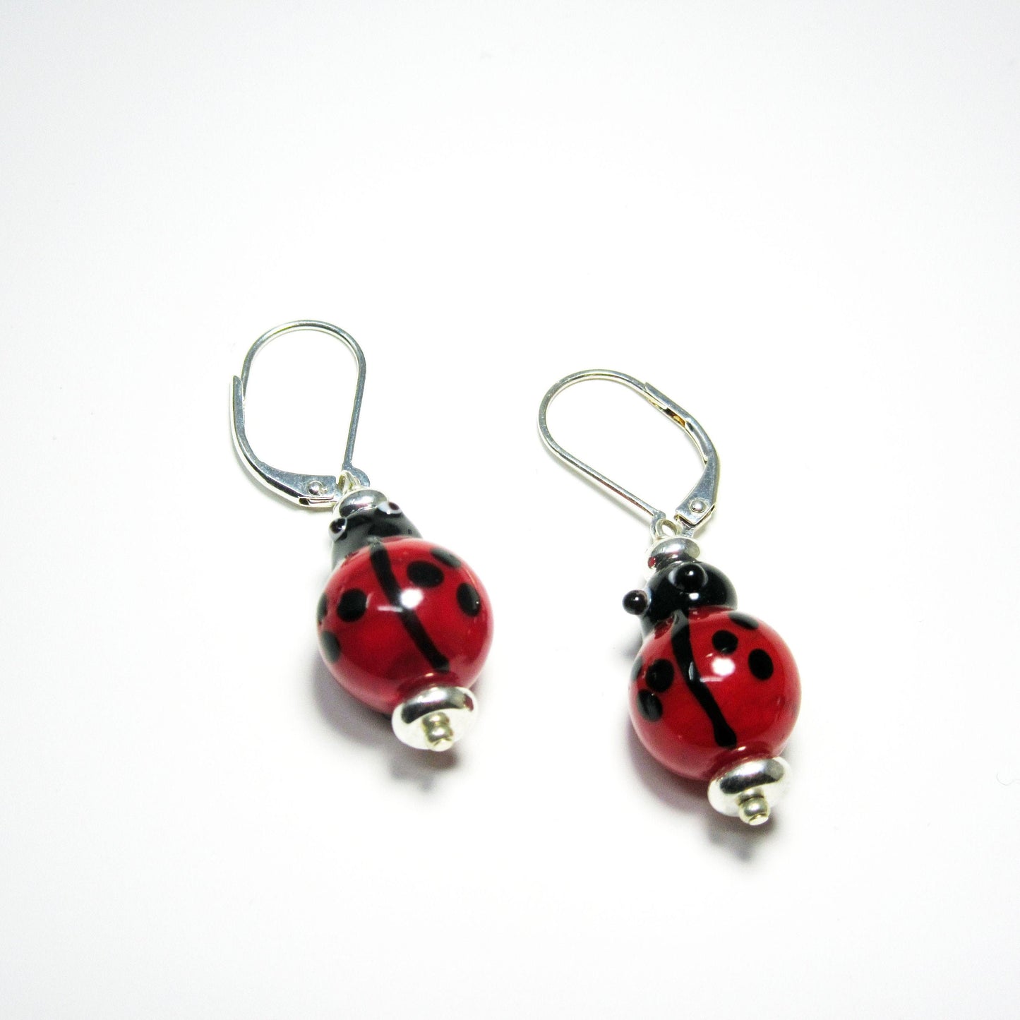 Lampworked Glass Ladybug Earrings: Sterling silver good luck jewelry featuring handmade red and black bead ladybugs on silver hooks, displayed on a white background.