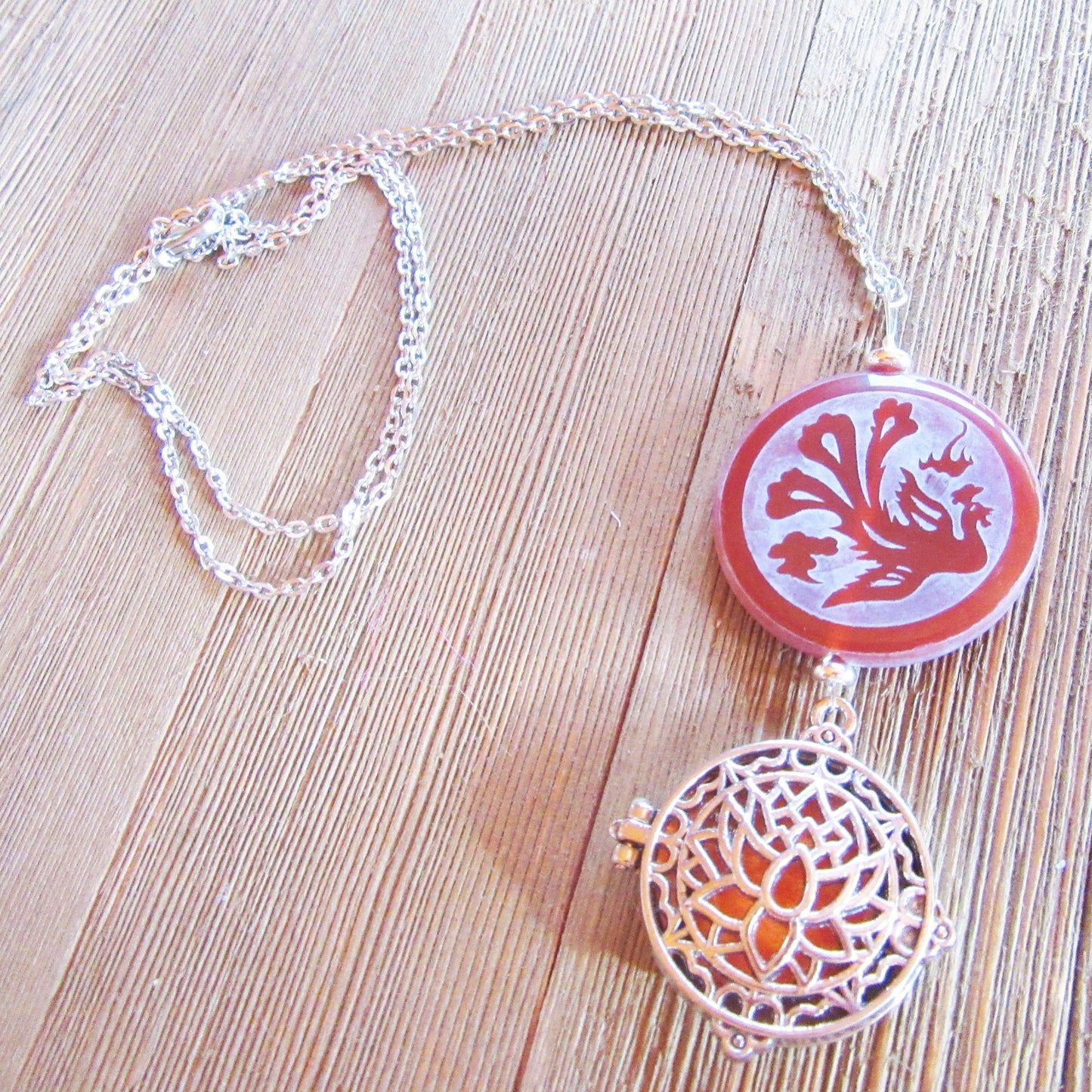 The Lotus Dragon & Peacock Aromatherapy Necklace features a round pendant with color-changing Zen jewelry, displayed on a light wooden surface.