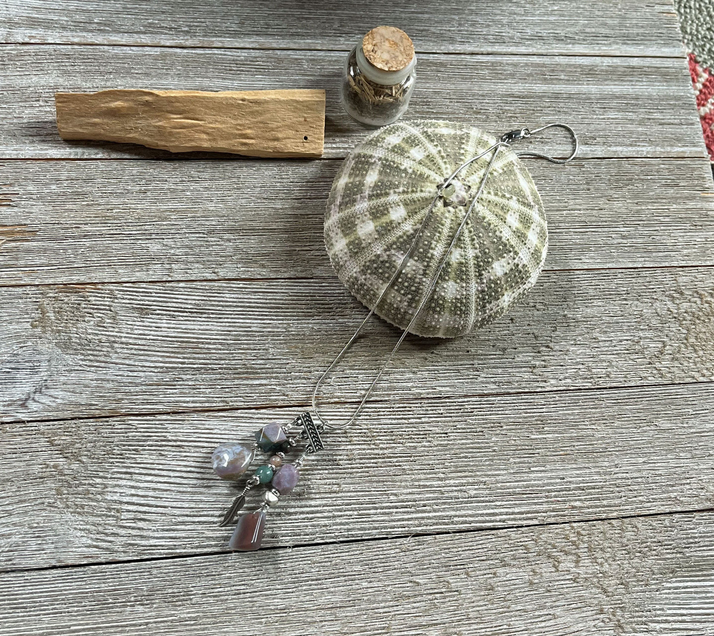 Close-up of the Fancy Jasper Triple Charm Pendant Necklace, highlighting its colorful stones and feather charm for spiritual connection.