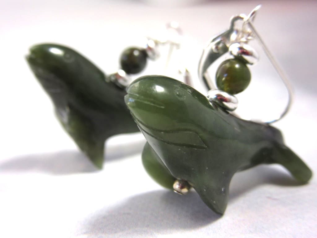 Close-up of nephrite stone humpback whale earrings, ideal for ocean enthusiasts.