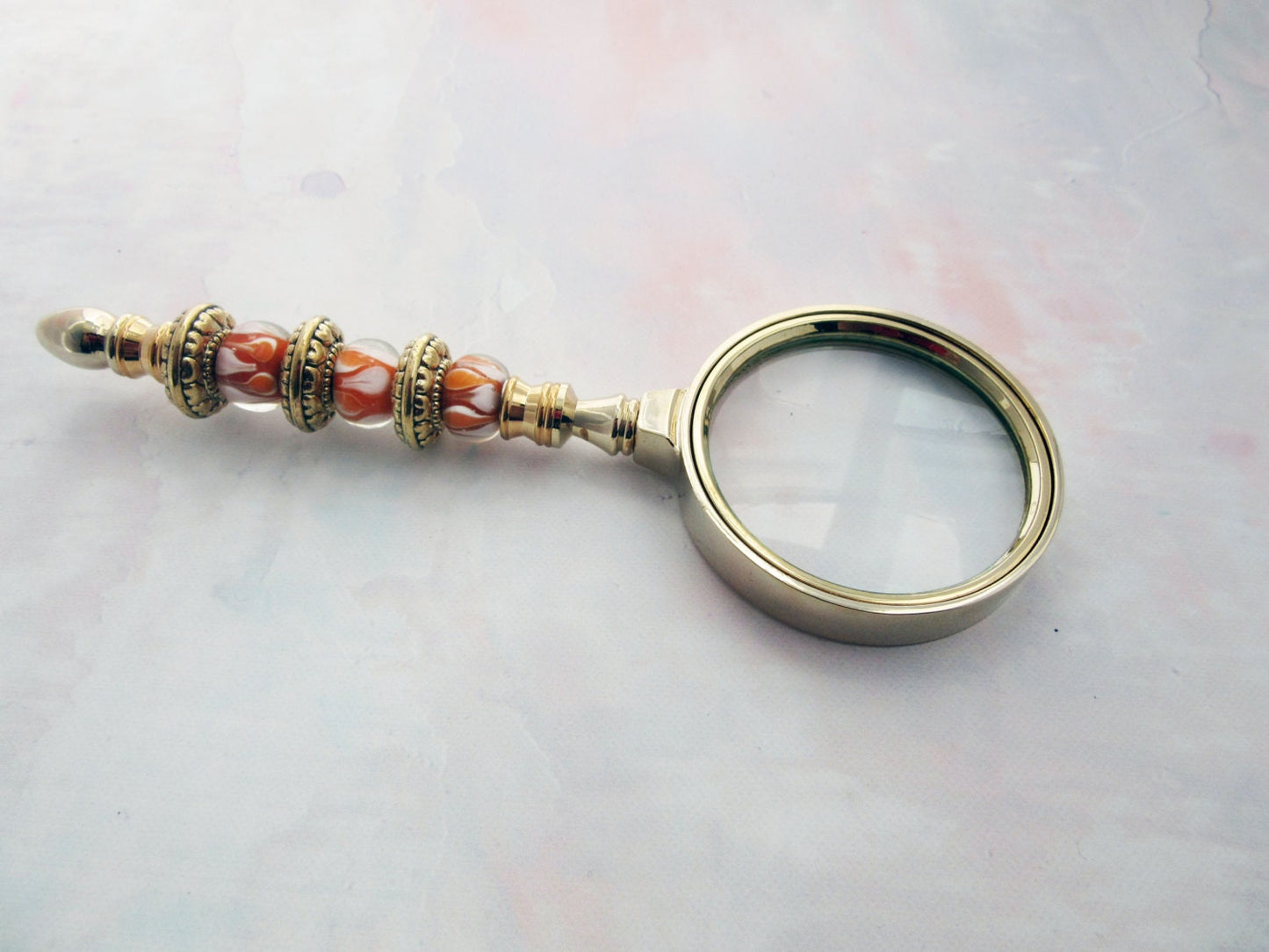 Golden Orange Bead Magnify Glass - A luxurious magnifier with a beaded sunburst orange handle and golden faceted glass, perfect as a unique gift for grandparents or moms.
