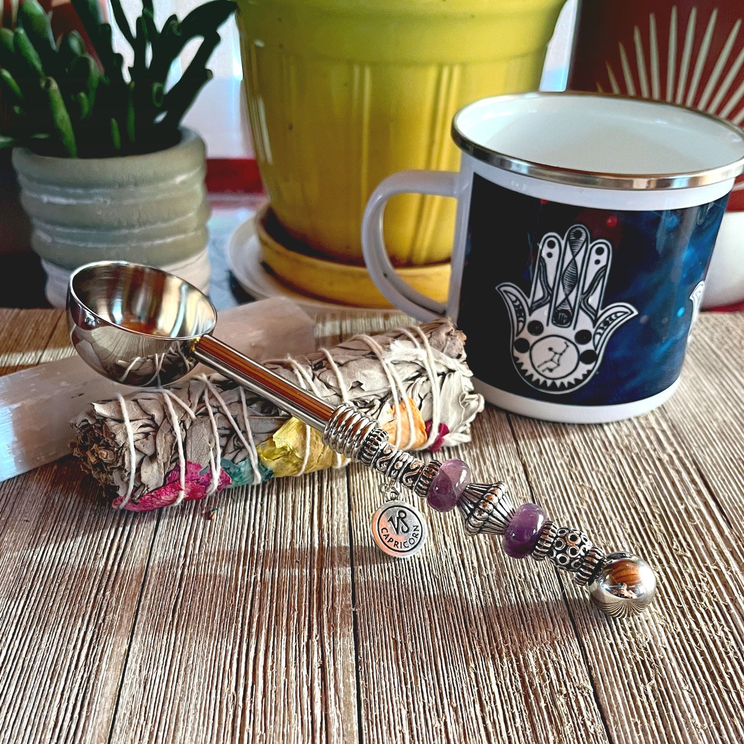 Foodie Gifts collection featuring a unique silver scoop with a beaded handle, placed next to colorful sage bundles, a decorative mug, and potted plants, ideal for culinary enthusiasts and stylish hosts.