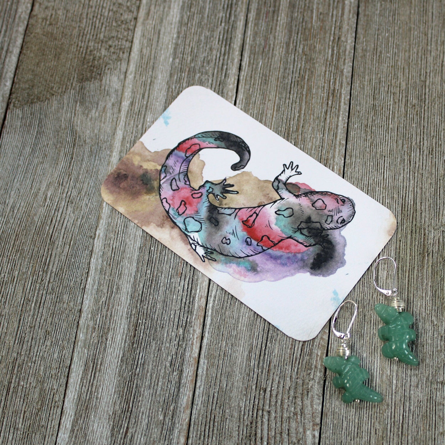 Artistic illustration of a vibrant lizard paired with handcrafted jade earrings, representing unique spiritual gifts. Ideal for enhancing your zen space, this image complements our Spiritual Gifts collection.