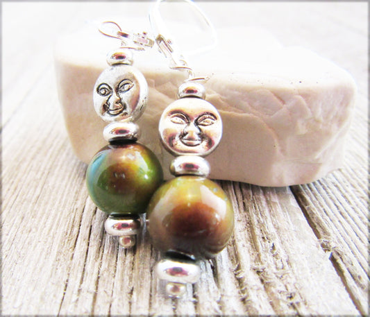 Spring Full Moon Silver Earrings with Color Changing Mood Beads showcase a lunar crescent moon face design and large green-brown mood beads, displayed on light wood with a white stone in the background.