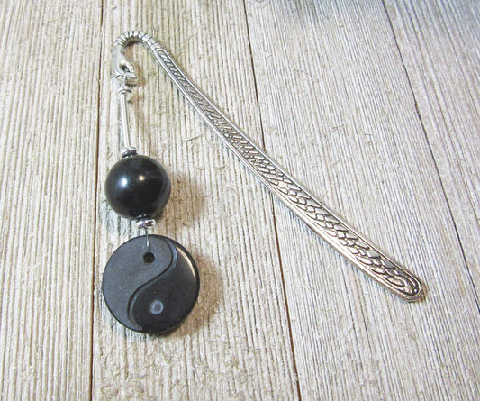 The Yin Yang Bookmark: Natural Stone Accents, Zen Gift Artisan Designed, features a silver metal body with textured handle, black round natural stone bead, and yin-yang charm, displayed on a light wood surface.