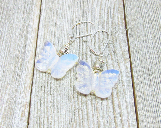 Handcrafted Rose Quartz Butterfly Earrings with sterling silver lever backs are elegantly displayed on a weathered wooden surface, showcasing butterfly-shaped rose quartz pendants and quality silver craftsmanship.