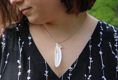Close-up of the White Feather Necklace, showcasing the delicate carved bone feather and pearls, symbolizing purity and protection.