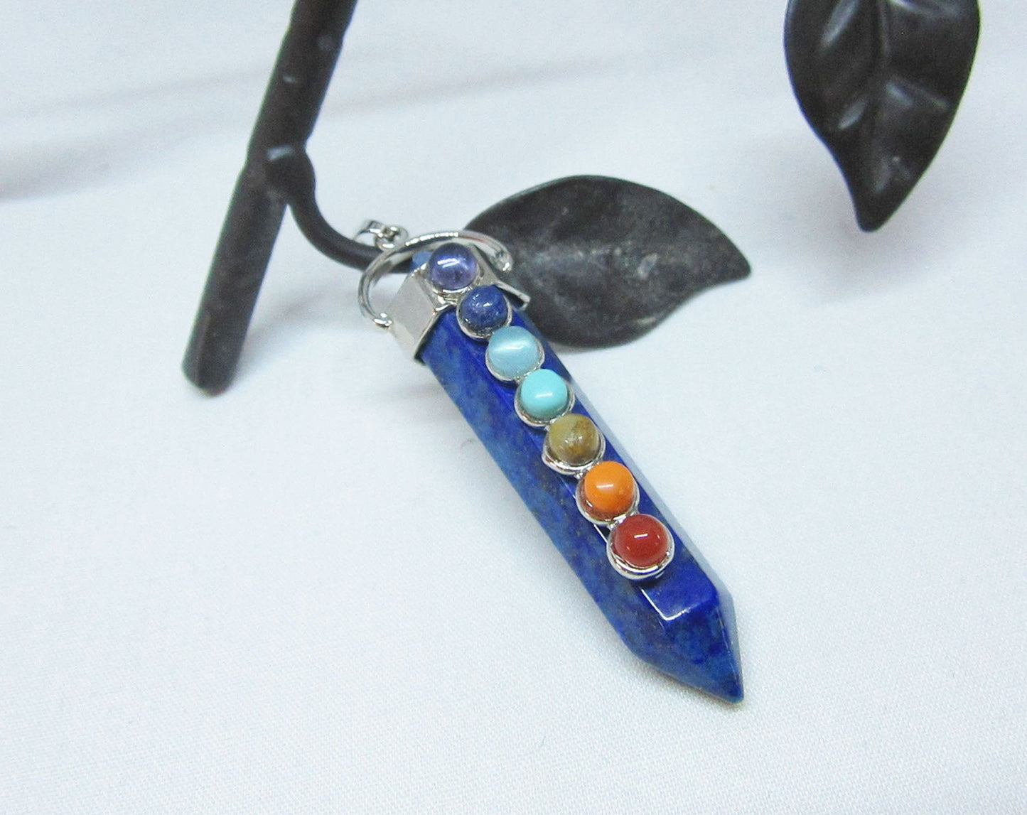 The Chakra Stones Pendant features seven colorful gemstones in a vertical design on a silver chain. This healing gemstone jewelry is ideal for yoga lovers and adds vibrant energy to your style.