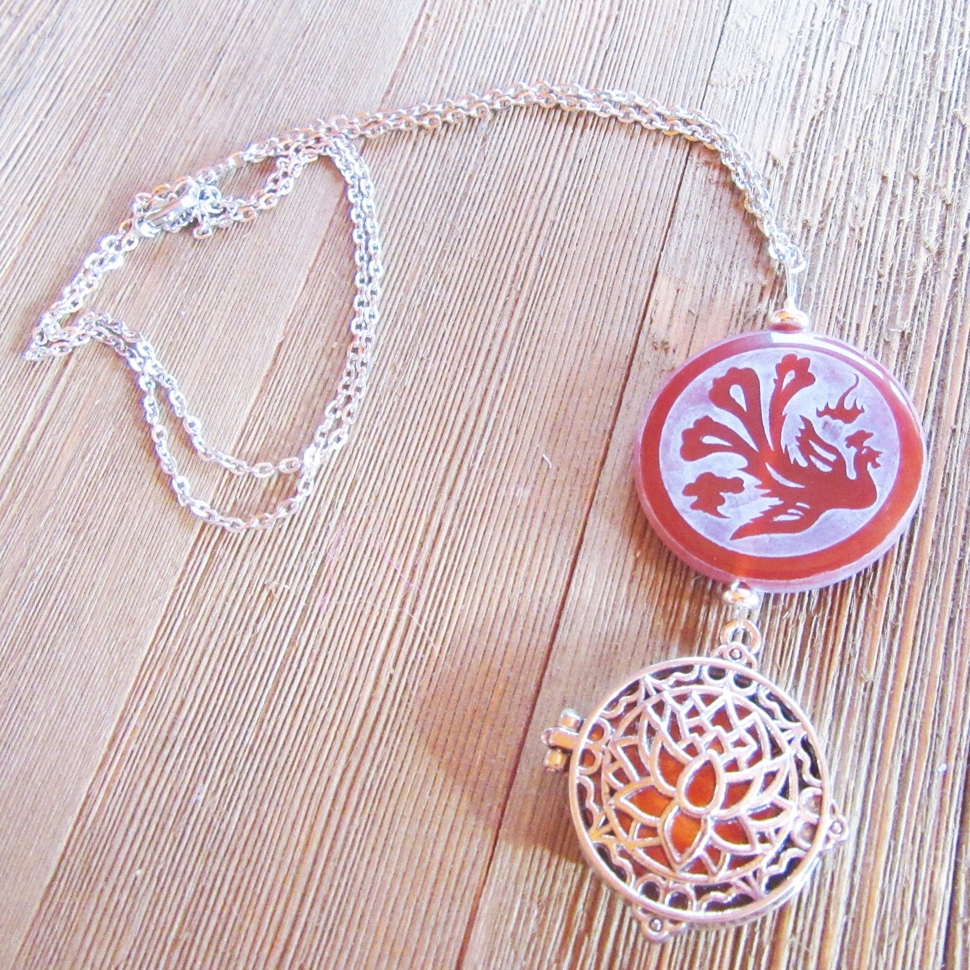 The Lotus Dragon & Peacock Aromatherapy Necklace features a round pendant with color-changing Zen jewelry, displayed on a light wooden surface.