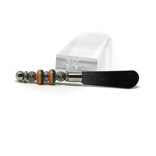 The Rainbow Pride Cheese Spreader Knife features a colorful, handcrafted handle—perfect as a fun kitchen accessory or unique gift for housewarmings and hosts, and ideal for charcuterie boards at any gathering.