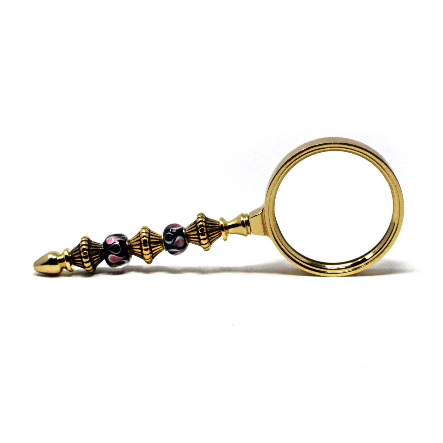 The Gold Beaded Magnifier is a handmade, stylish desk accessory with ornate gold and black-and-pink beaded details on the handle, offering a crystal-clear image and displayed on a white background.