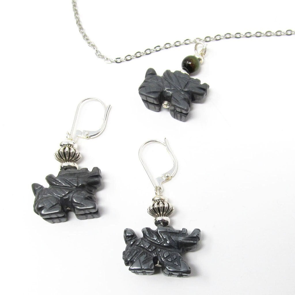 The Handcrafted Hematite Dragon Jewelry Set includes sterling silver earrings, a necklace, and a bangle. Each piece features dark hematite accents and is beautifully displayed on a white background.