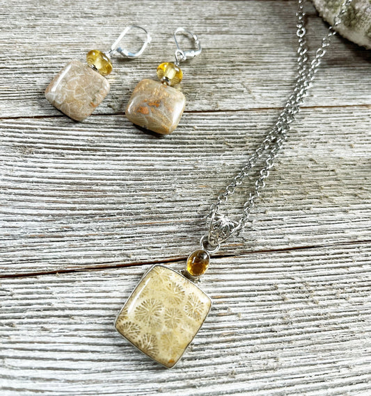The Fossil Coral Jewelry Set features a 24" necklace with square beige fossil stone pendants, amber beads, and matching topaz sterling silver earrings, beautifully displayed on rustic wooden boards.