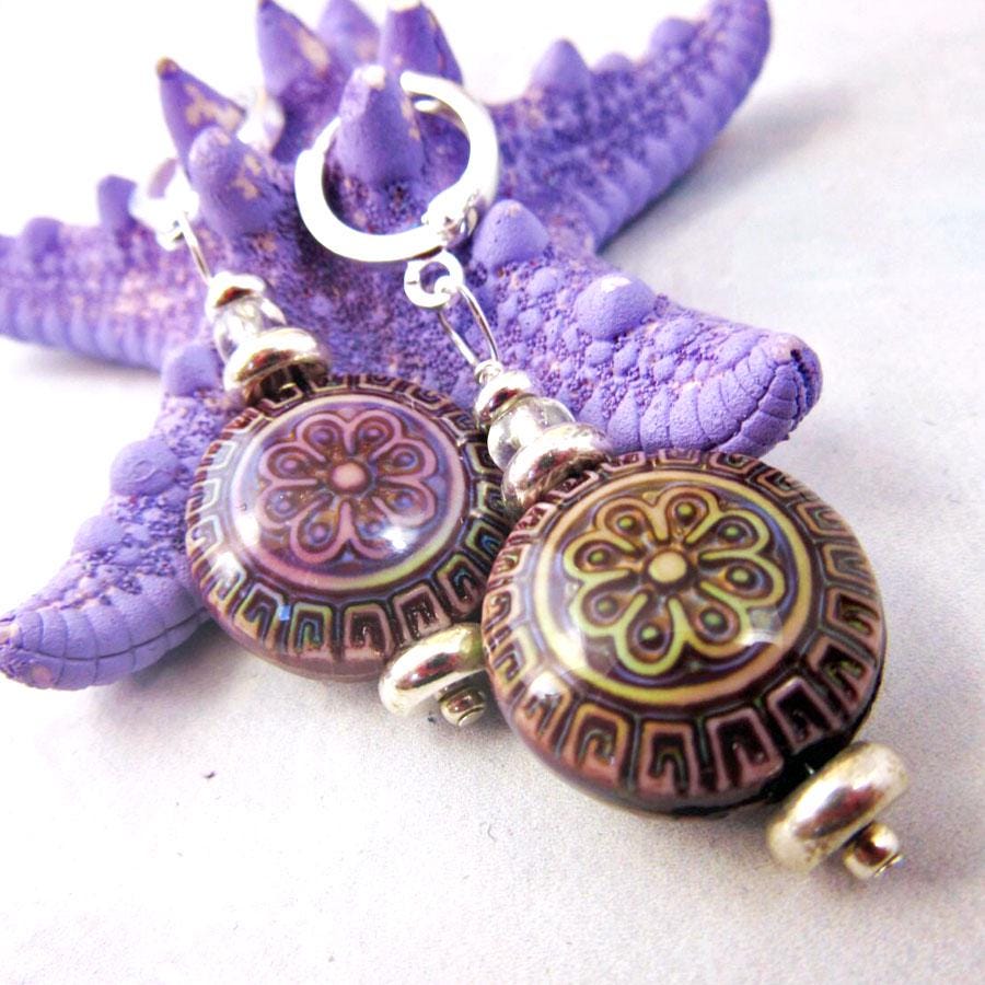 The Color Changing Mandala Earrings feature sterling silver lever backs and intricate floral and geometric designs, displayed on a textured purple starfish. This boho jewelry pair has round, patterned beads that shift color for a unique look.