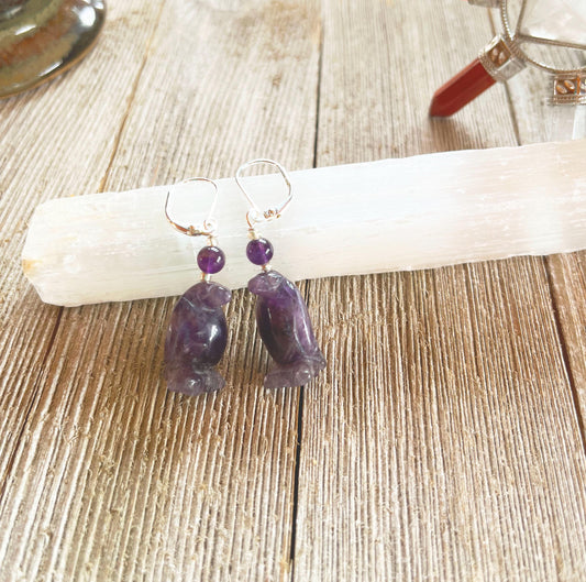 Purple Amethyst Penguin Earrings—featuring bear-shaped pendants and round beads, displayed on a white selenite wand on rustic wood. These playful earrings are perfect animal lover jewelry for any nature enthusiast.