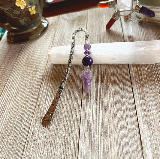 The Amethyst Bookmark: Artisan Designed Divine Goddess Celestial Gift features engraved metal, purple beads, and an amethyst angel charm, pictured on a white selenite stick—making it a perfect celestial-themed present.