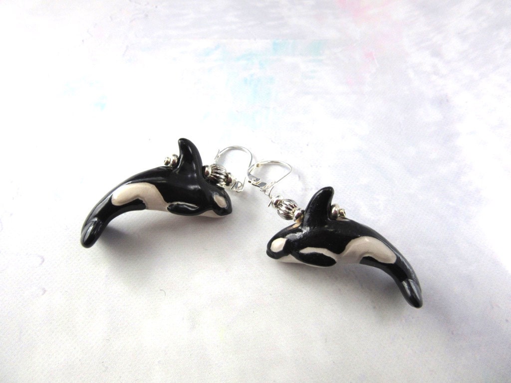 Hand Painted Ocean Themed Ceramic Whale Earrings for Animal Lovers shaped like black and white orcas with silver hooks, featuring intricate whale details, displayed on a light textured surface.