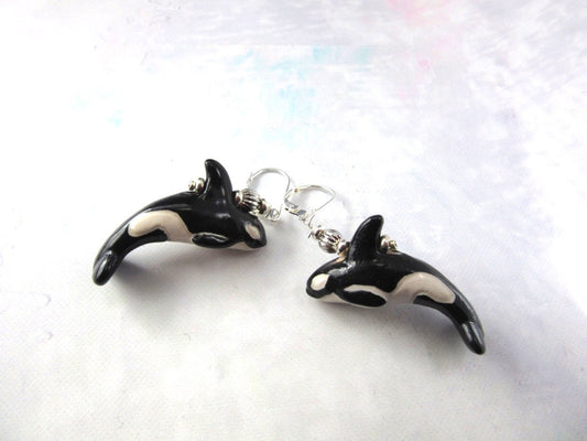 Hand Painted Ocean Themed Ceramic Whale Earrings for Animal Lovers shaped like black and white orcas with silver hooks, featuring intricate whale details, displayed on a light textured surface.
